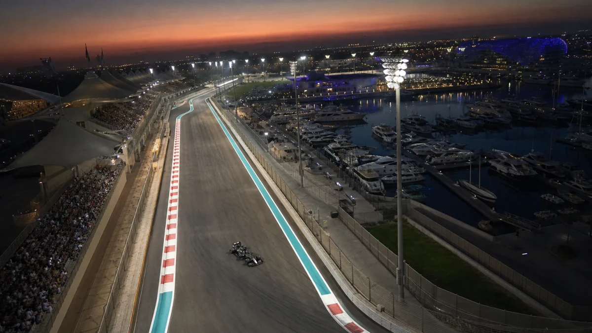 Illustration: f1-bil på Yas Marina i skymning med upplyst depåbyggnad